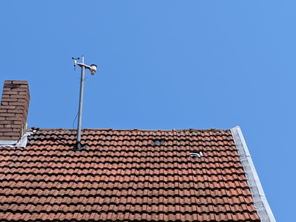 Die ADS-B-Antenne auf dem Dach, montiert am Kaminschacht, vor blauem Himmel.