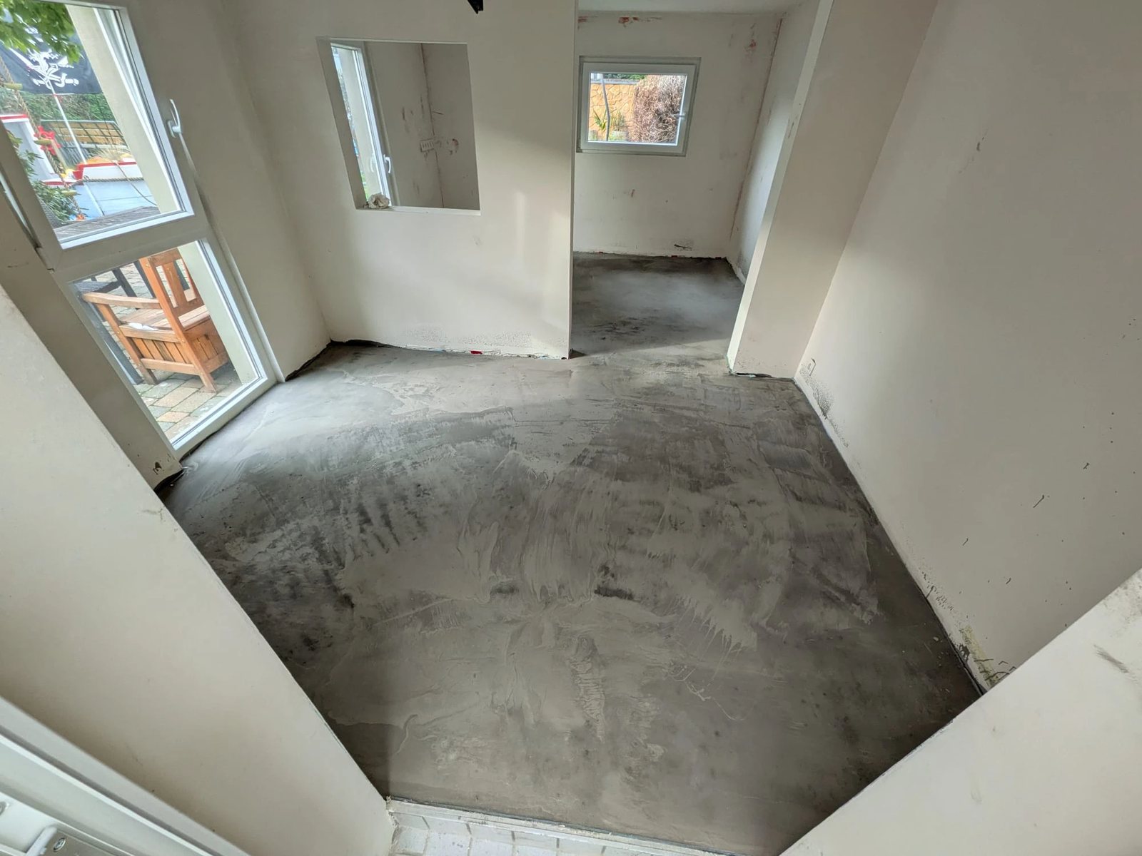 Der fertige Boden von oben. Durchgehend grau und eben, durch beide Räume bis an die Wände.