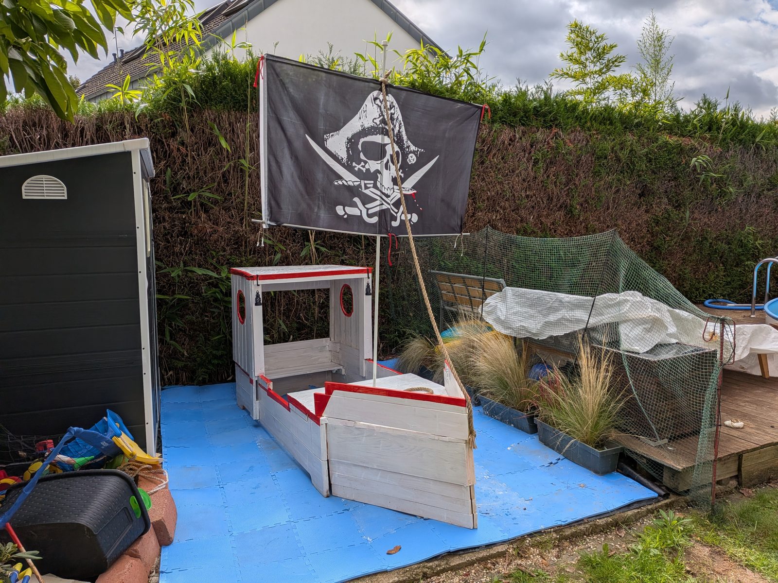 Das fertig gestrichene Schiff in Weiß und Rot, mit Bullaugen und Laternen an der Kajüte, Tau vom Mast zum Bug und großem schwarzen Piratensegel